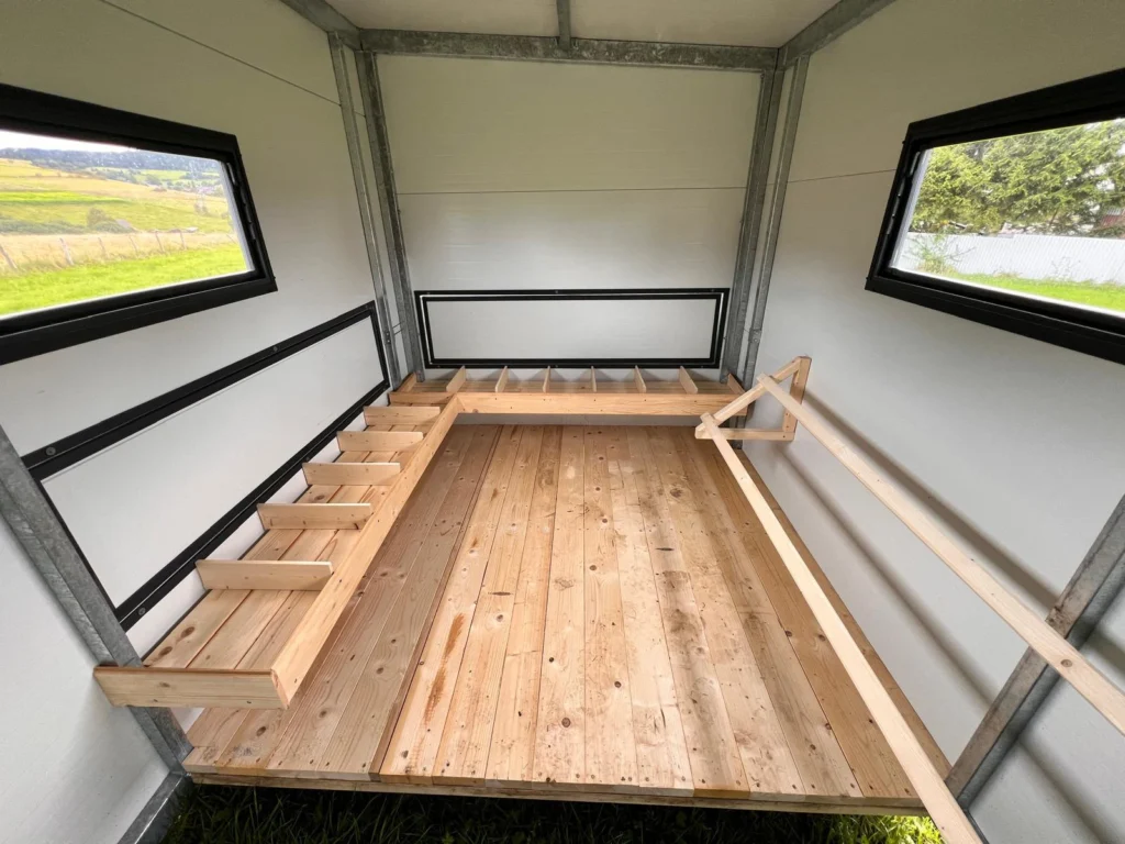 Drewniany podest oraz boksy na gniazda w dużym mobilnym kurniku